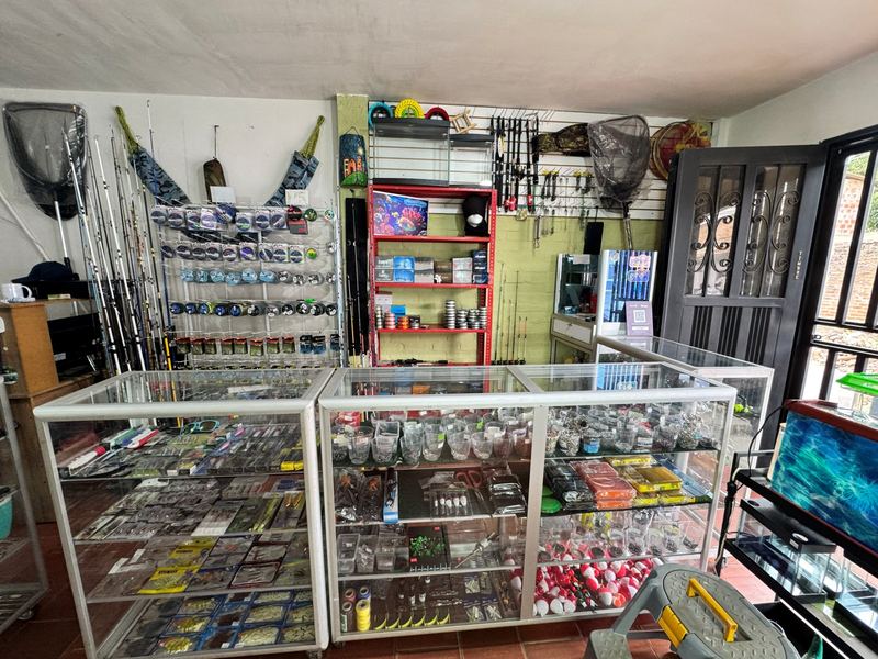 Sección de pesca deportiva con cañas, señuelos, anzuelos y vitrinas de accesorios